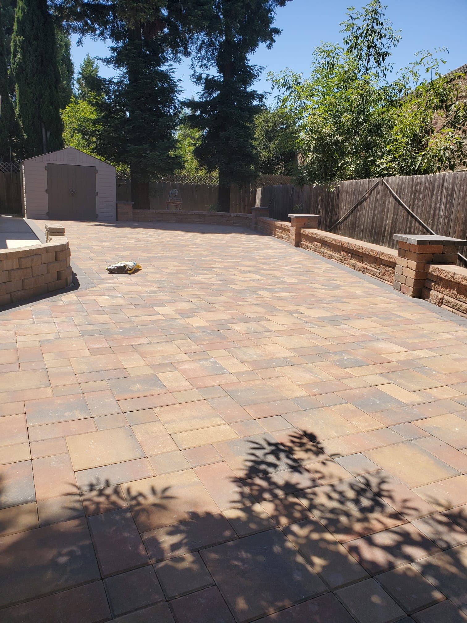 Expansive interlocking paver patio bordered by stacked-stone seat walls